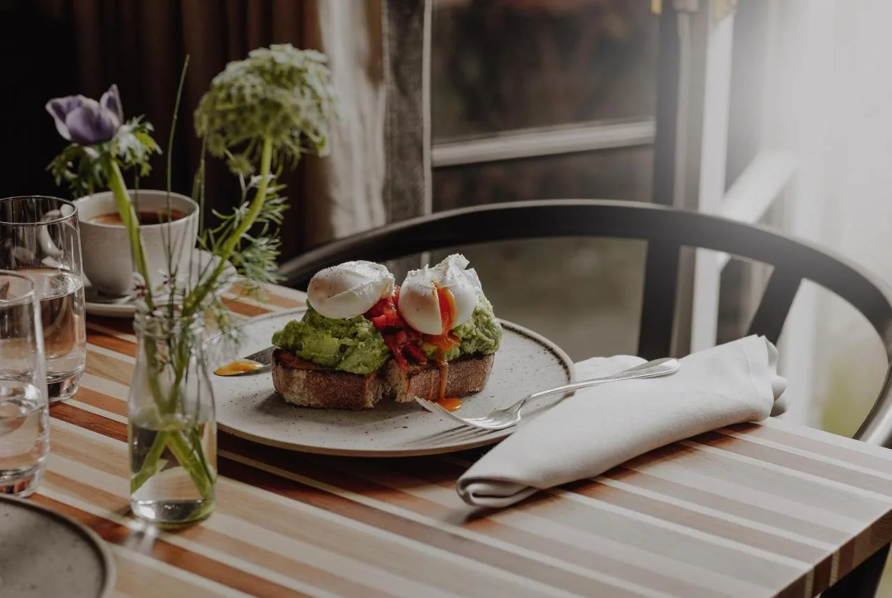 a table with a plate with a sandwich on it at No 15 by GuestHouse, Bath in Bath
